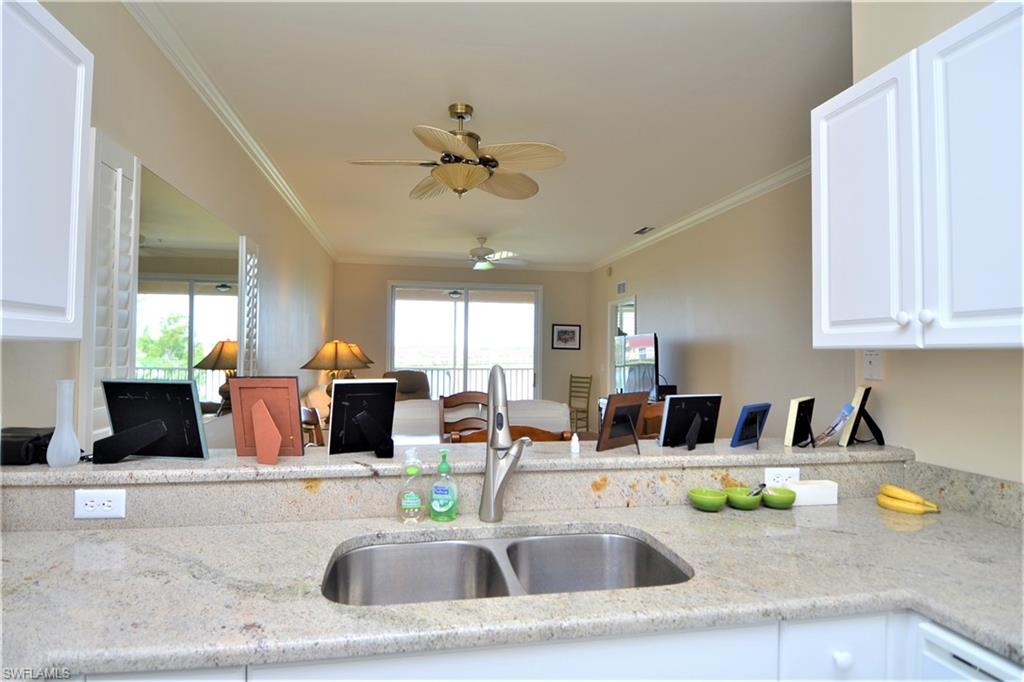 2750 Cypress Trace Circle, Unit 2636 Naples, FL 34119 - Photo 12 of 26 a kitchen with stainless steel appliances granite countertop a sink a stove cabinets and living room view