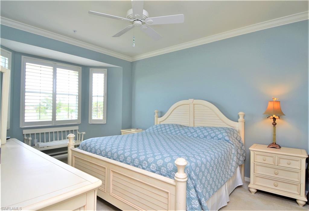 2750 Cypress Trace Circle, Unit 2636 Naples, FL 34119 - Photo 16 of 26 a bedroom with a bed and a chandelier