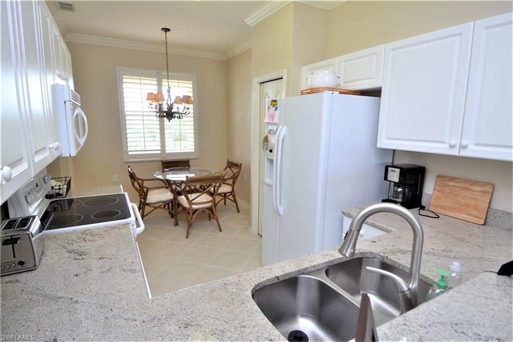 2750 Cypress Trace Circle, Unit 2636 Naples, FL 34119 - Photo 9 of 26 a kitchen with refrigerator a sink and chairs