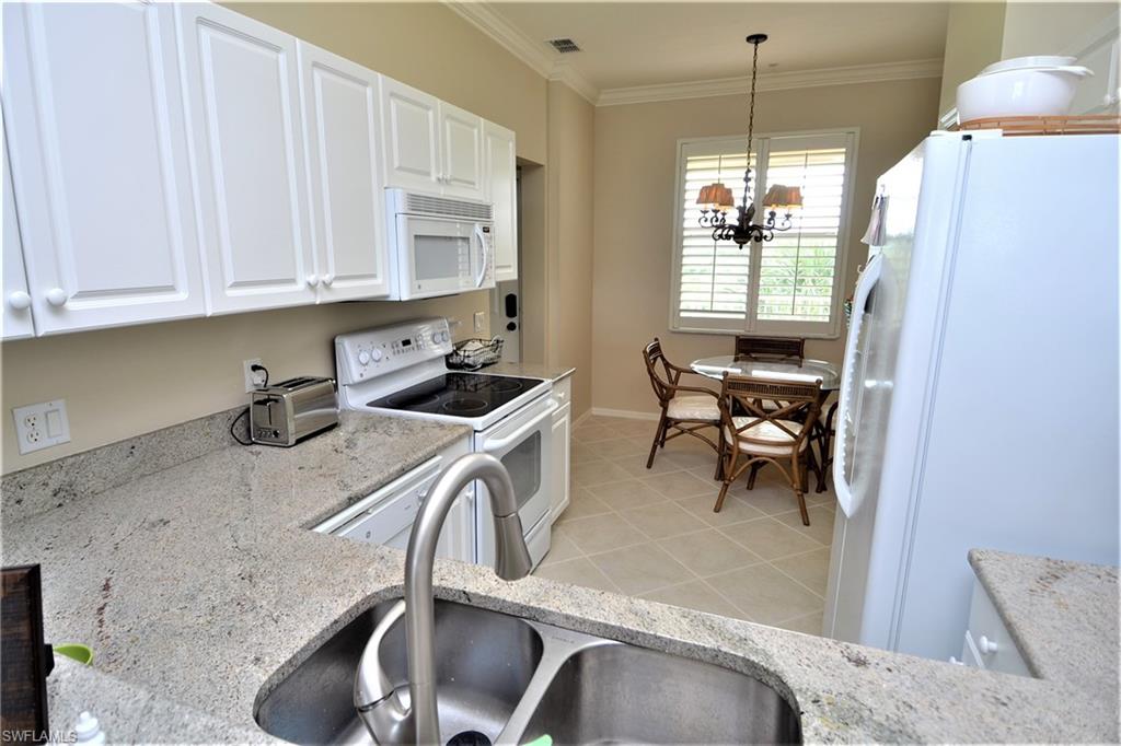 2750 Cypress Trace Circle, Unit 2636 Naples, FL 34119 - Photo 10 of 26 a kitchen with stainless steel appliances granite countertop a sink a stove and a refrigerator