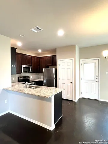 a kitchen with stainless steel appliances granite countertop a sink a stove a refrigerator a center island with wooden floor