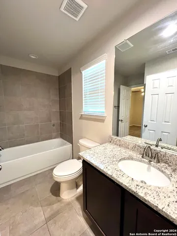 a bathroom with a granite countertop sink a toilet a mirror and bathtub