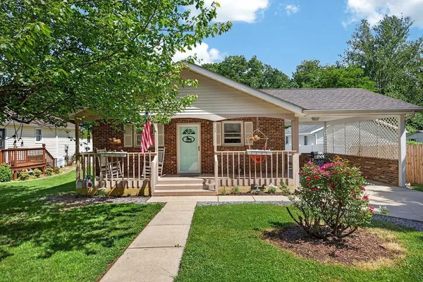 a view of a house with a small yard plants and large tree