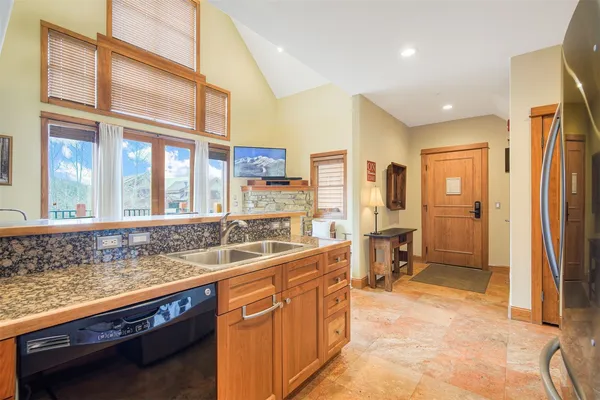 a large kitchen with kitchen island a large window a sink and stainless steel appliances