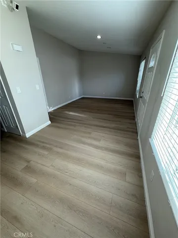 en empty room with wooden floor and windows