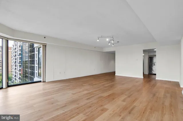 a view of an empty room with wooden floor and a window