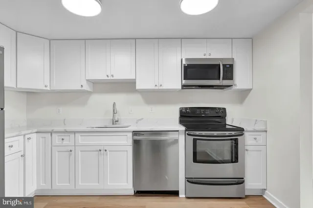 a kitchen with white cabinets and stainless steel appliances