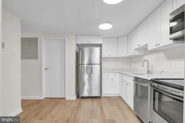 a kitchen with stainless steel appliances granite countertop a refrigerator sink and white cabinets