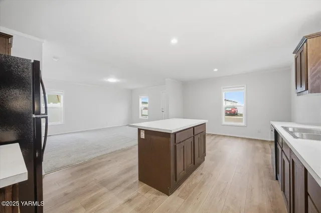a view of kitchen with stainless steel appliances kitchen island a sink dishwasher a refrigerator and a stove with wooden floor