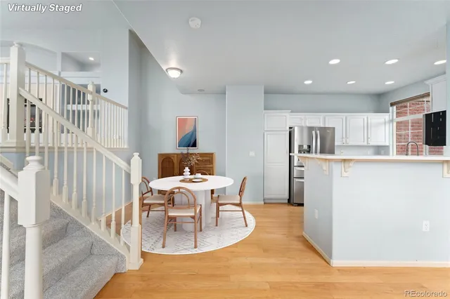 a dining room with kitchen island stainless steel appliances kitchen island granite countertop a table chairs and a refrigerator