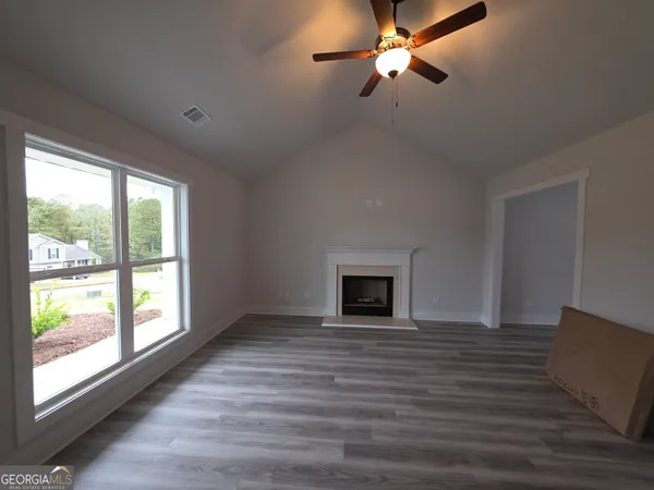 a view of empty room with wooden floor and fan