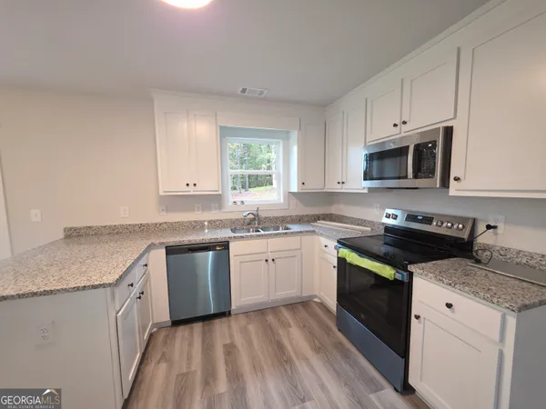 a kitchen with granite countertop cabinets stainless steel appliances and a sink