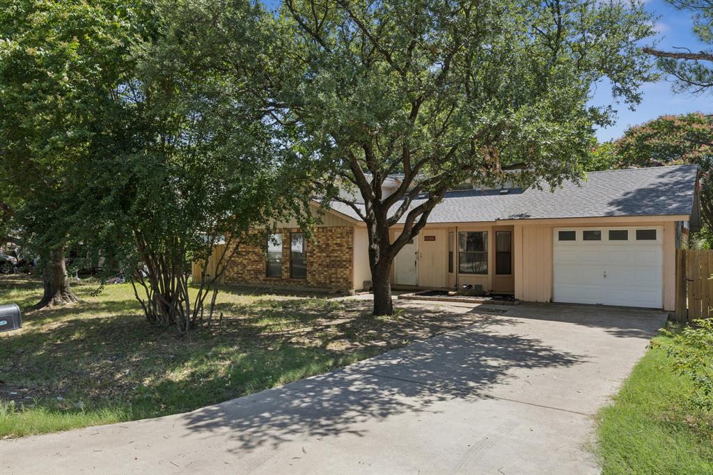 View of front of house with an attached garage, concrete driveway, and a shingled roof