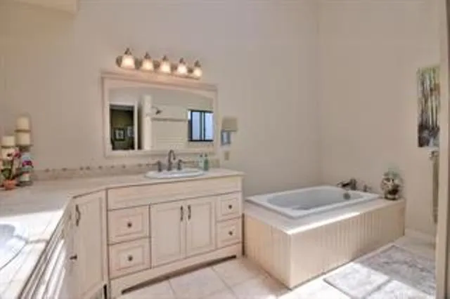 a spacious bathroom with a granite countertop sink mirror and bathtub