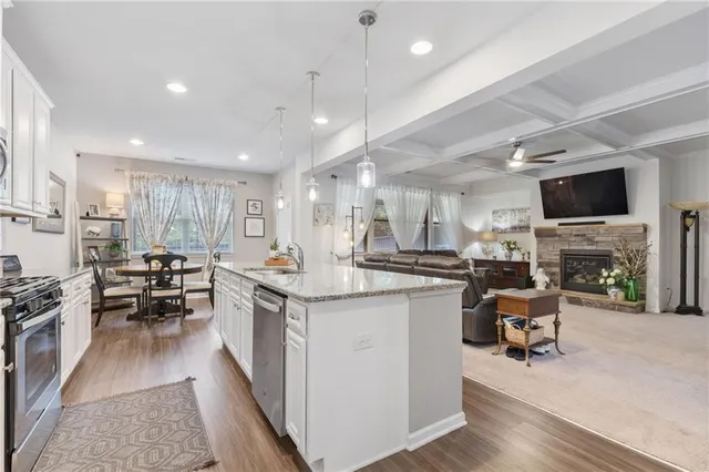 a kitchen with stainless steel appliances a stove a sink dishwasher a oven with white cabinets and wooden floor