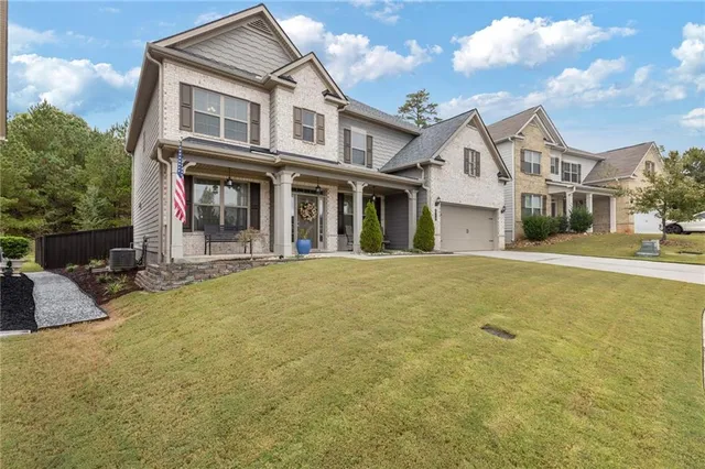 a view of a white house with large trees and plants