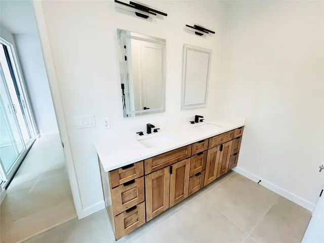 a bathroom with double vanity sink a mirror and a bathtub