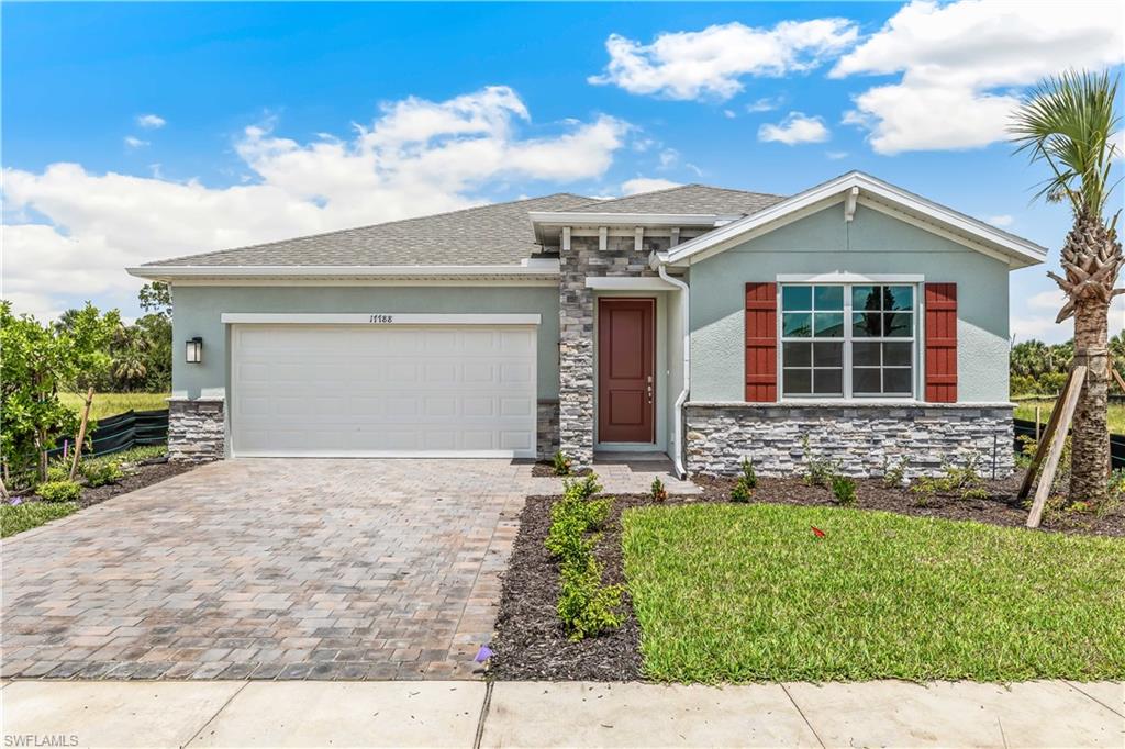 17788 Shade Tree Loop Punta Gorda, FL 33982 - Photo 1 of 44 View of front of home featuring stone siding, stucco siding, decorative driveway, and a garage