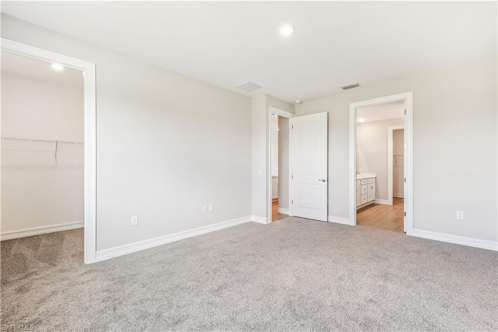 17788 Shade Tree Loop Punta Gorda, FL 33982 - Photo 12 of 44 Unfurnished bedroom featuring a walk in closet, light carpet, ensuite bathroom, and recessed lighting