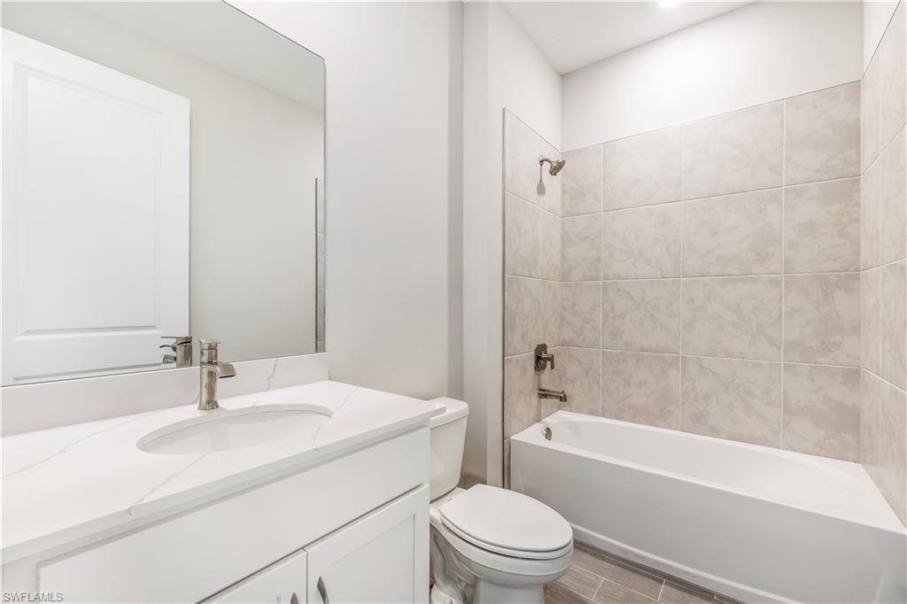 17788 Shade Tree Loop Punta Gorda, FL 33982 - Photo 13 of 44 Bathroom with bathtub / shower combination, vanity, and wood finish floors