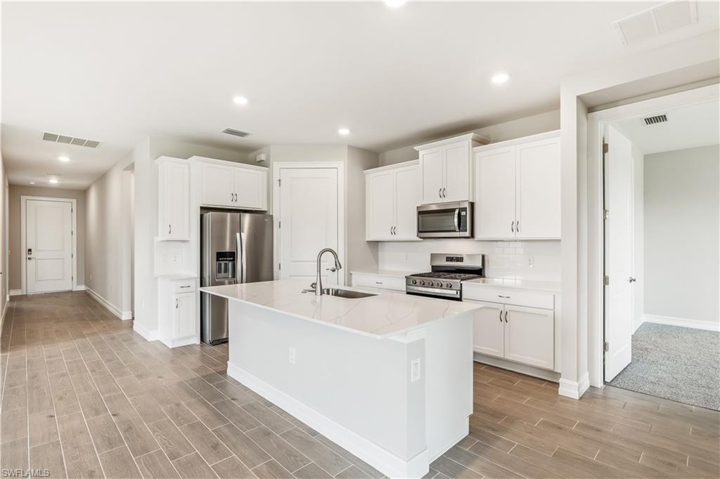 17788 Shade Tree Loop Punta Gorda, FL 33982 - Photo 7 of 44 Kitchen with appliances with stainless steel finishes, recessed lighting, a center island with sink, white cabinetry, and backsplash
