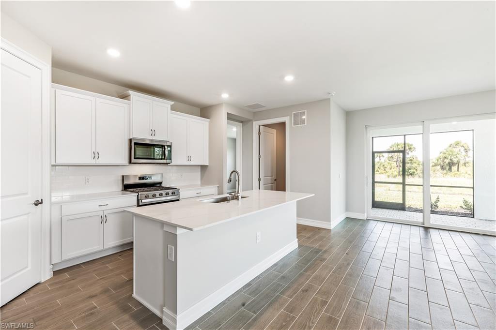 17788 Shade Tree Loop Punta Gorda, FL 33982 - Photo 8 of 44 Kitchen featuring a kitchen island with sink, wood finish floors, stainless steel appliances, recessed lighting, and white cabinets