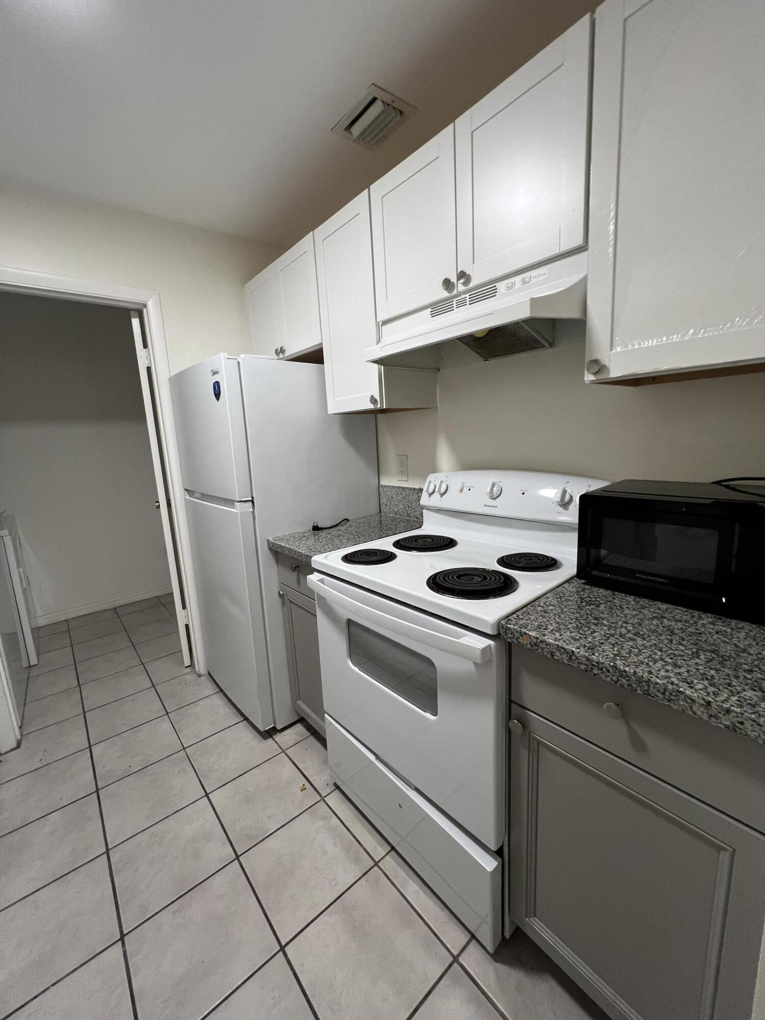 17355 Bush Road, Unit F Jupiter, FL 33458 - Photo 5 of 21 a kitchen with stainless steel appliances granite countertop a stove a refrigerator and a cabinets