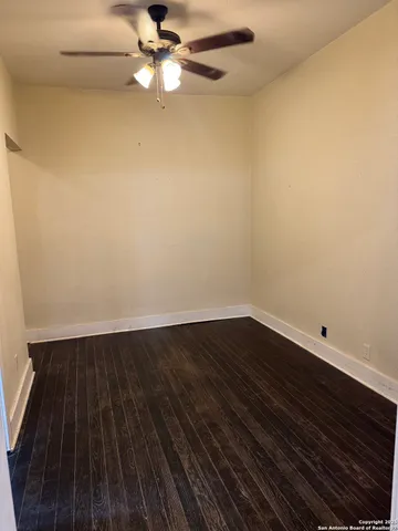 an empty room with wooden floor and fan