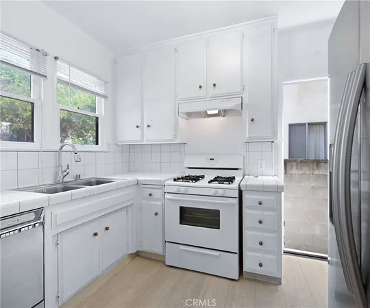 a kitchen with cabinets appliances a sink and a window