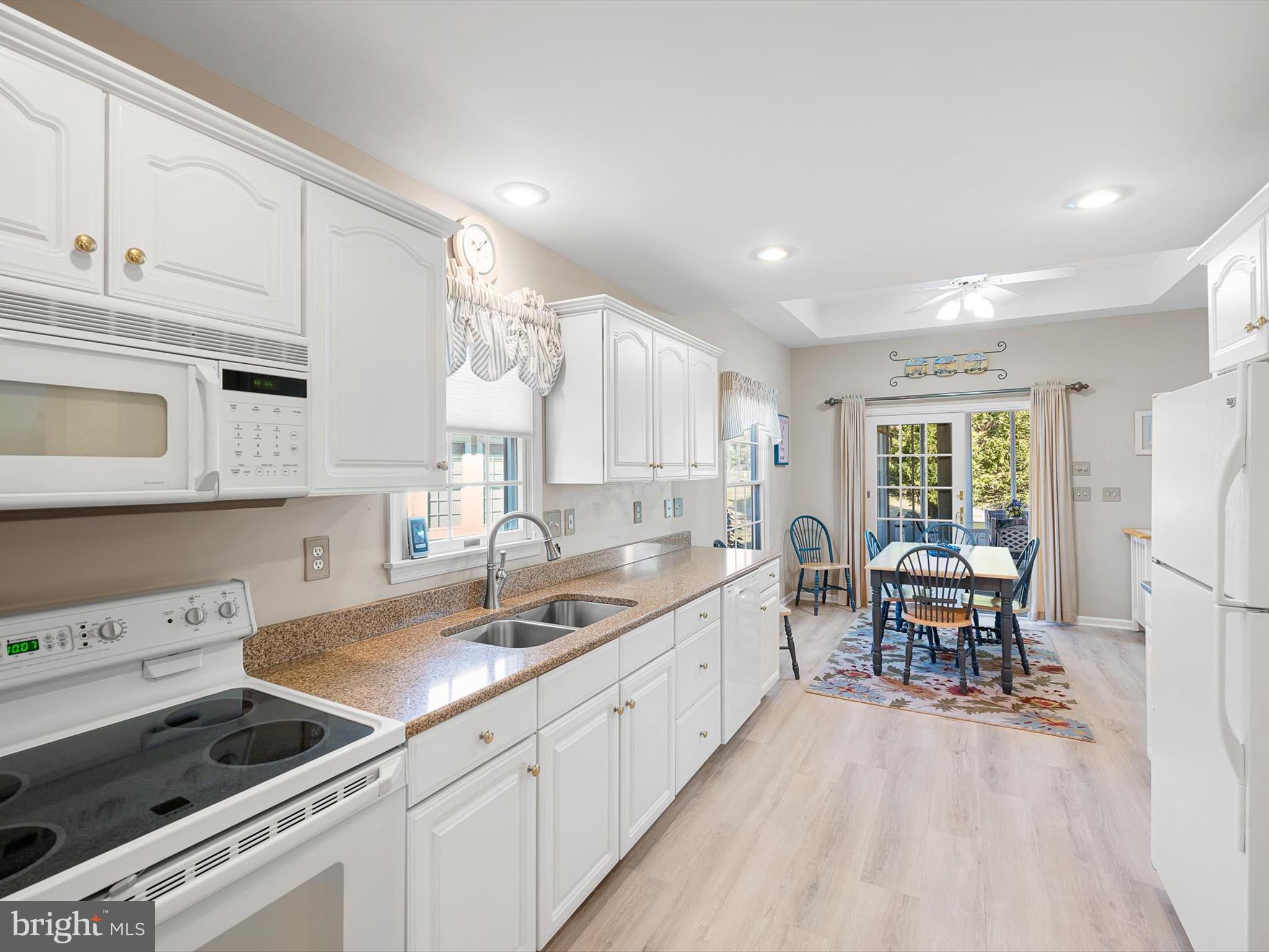 304 Walkabout Road Bethany Beach, DE 19930 - Photo 7 of 62 a kitchen with a stove a sink dishwasher a refrigerator and white cabinets with wooden floor