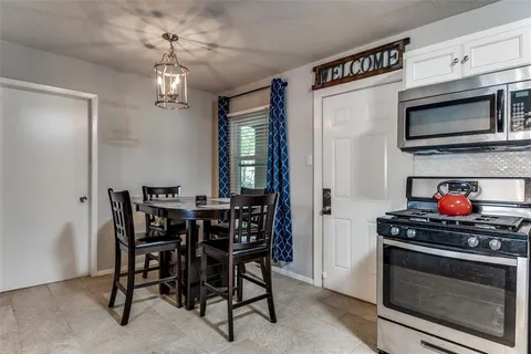 a kitchen with stainless steel appliances a stove a microwave and a dining table