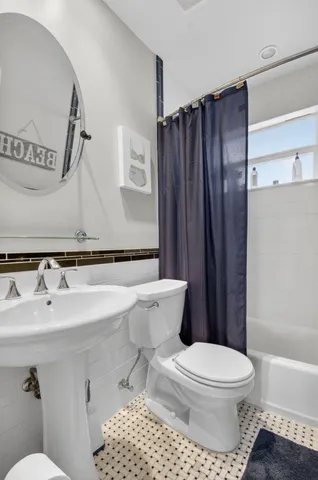 a bathroom with a sink a toilet a mirror and shower