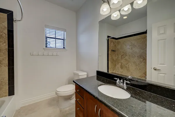 a bathroom with a granite countertop sink toilet a mirror and a shower