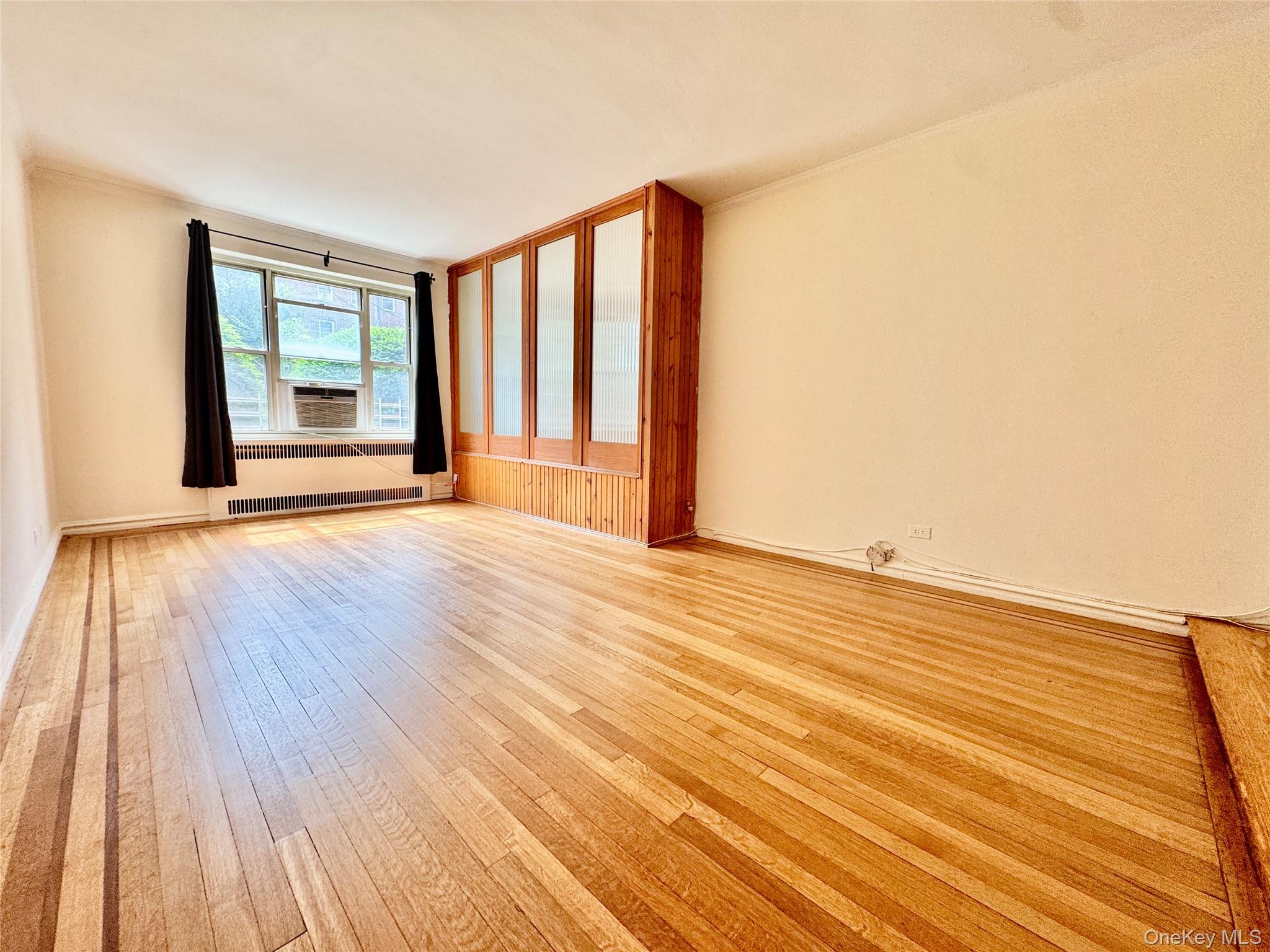 113-14 72nd Road, Unit 1M Queens, NY 11375 - Photo 4 of 20 a view of an empty room with wooden floor and a window