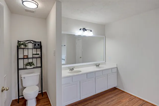 a spacious bathroom with a double vanity sink a toilet and a mirror