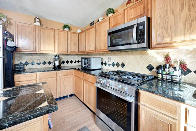 a kitchen with stainless steel appliances granite countertop a stove a sink and a microwave