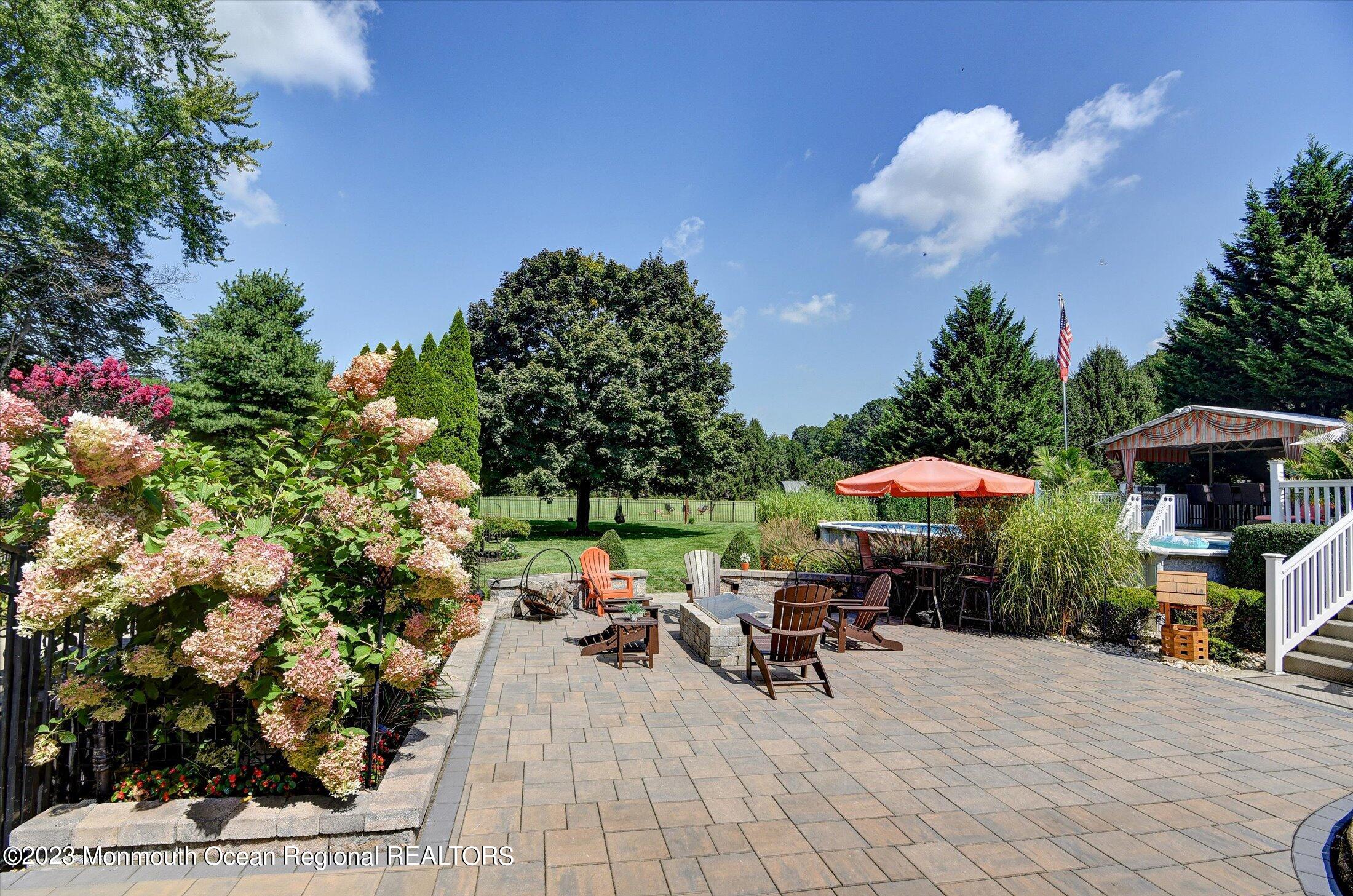 535 Brickyard Road Freehold, NJ 07728 - Photo 25 of 52 a view of a tables and chairs under an umbrella in backyard of the house