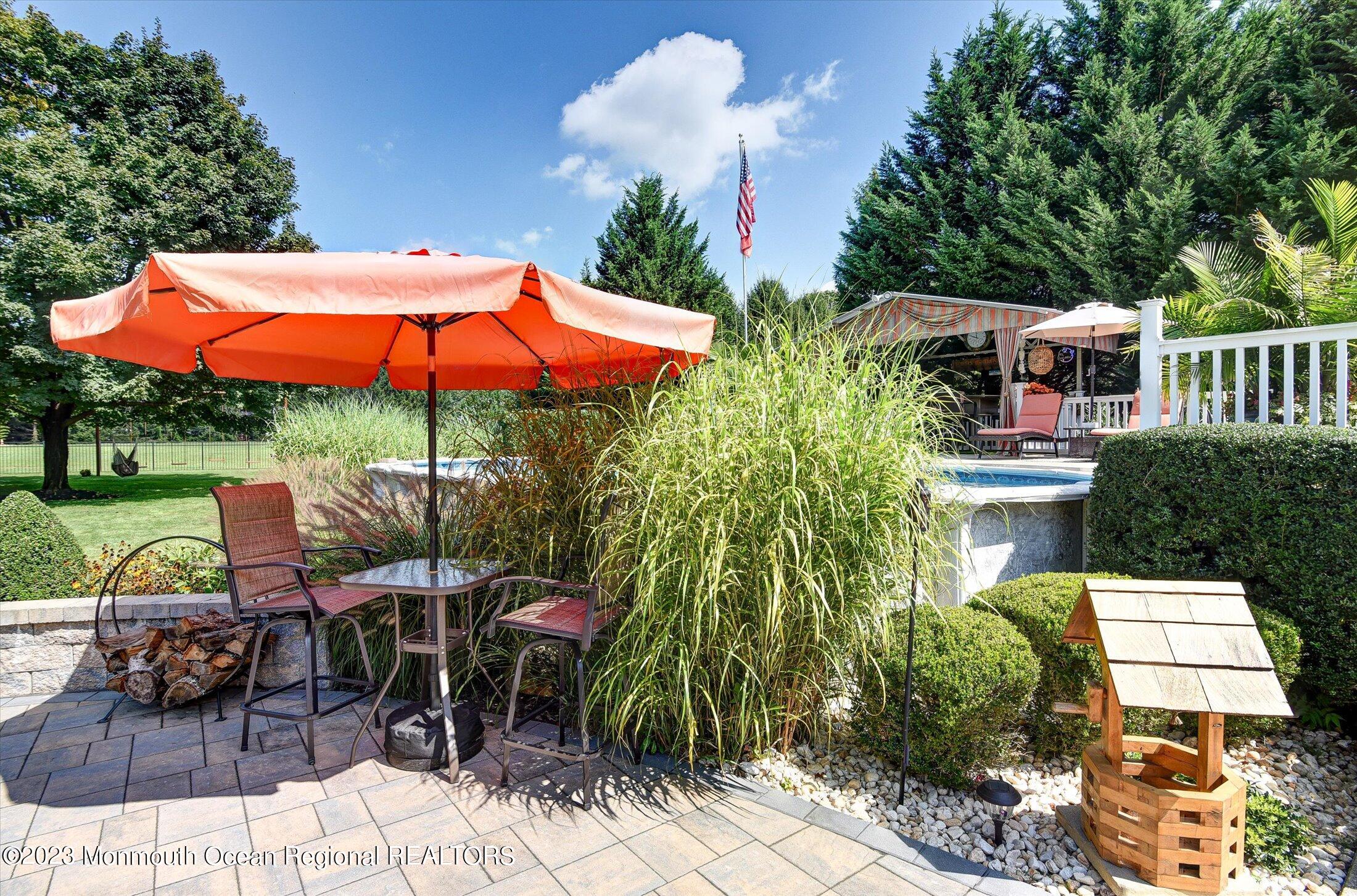 535 Brickyard Road Freehold, NJ 07728 - Photo 27 of 52 a view of a patio with table and chairs under an umbrella with a fire pit