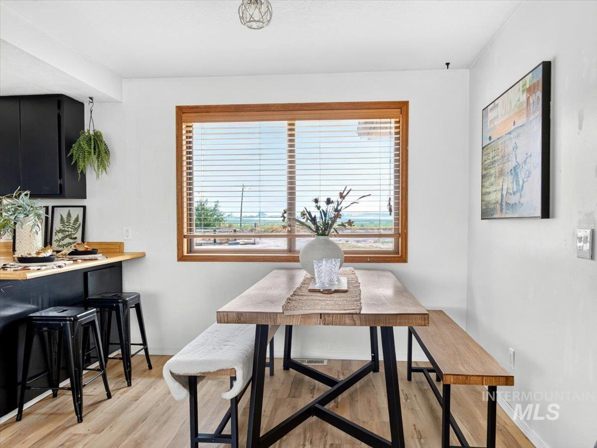 8989 Hillview Road Emmett, ID 83617 - Photo 15 of 50 Eat-in kitchen area featuring wood-finish flooring, a wood-frame window with horizontal blinds, and a built-in breakfast bar with a wood-finish countertop