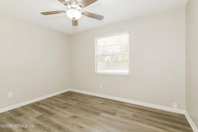 an empty room with a window and a ceiling fan