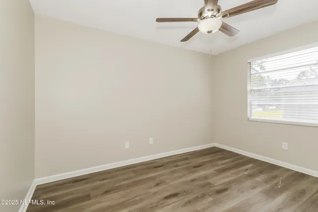 an empty room with a window and a fan