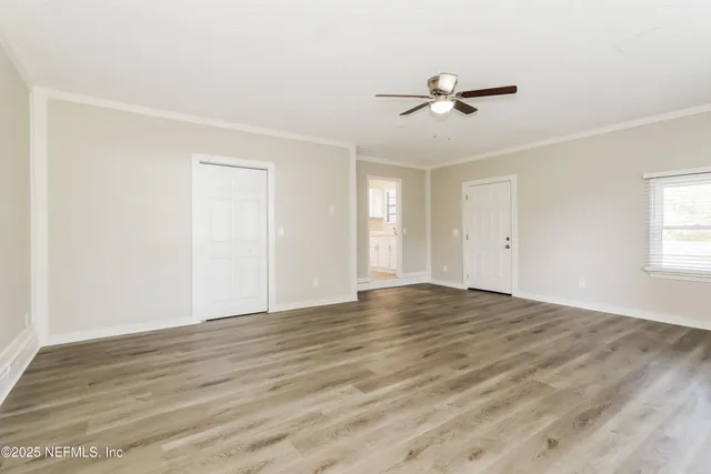 a view of empty room with wooden floor and fan