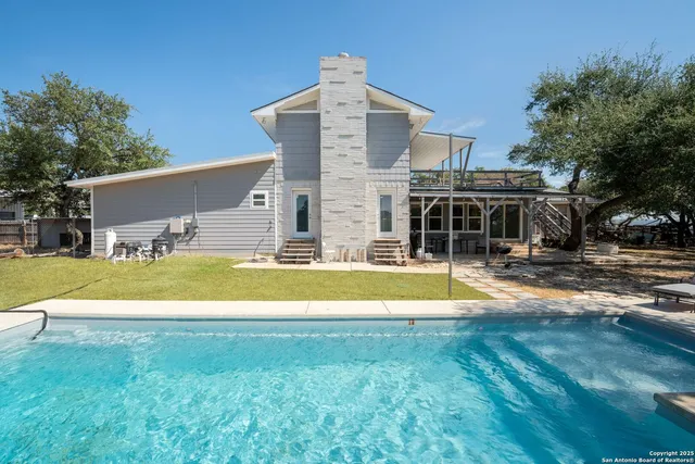 a view of swimming pool with lawn chairs and wooden fence