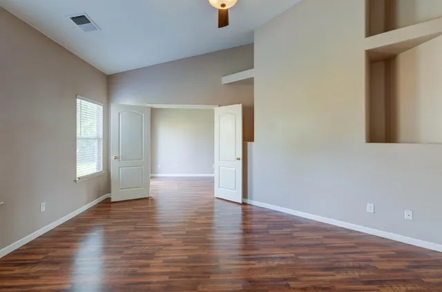 a view of an empty room with wooden floor and a window