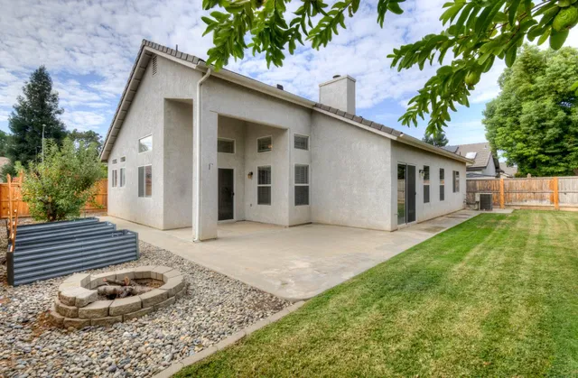 a backyard of a house with wooden fence and a tree