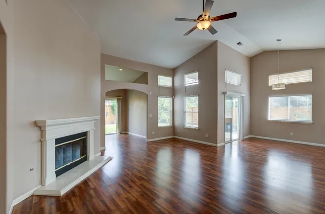 a view of an empty room with wooden floor fireplace and a window