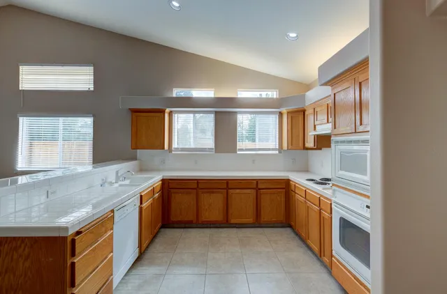 a large kitchen with stainless steel appliances granite countertop a sink and cabinets