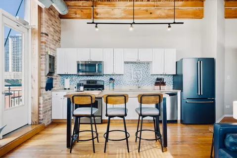 a kitchen with stainless steel appliances granite countertop a table chairs in it and wooden floors