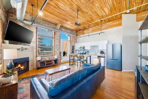 a living room with stainless steel appliances furniture fireplace and flat screen tv
