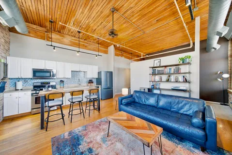 a living room with stainless steel appliances kitchen island granite countertop furniture and a wooden floor